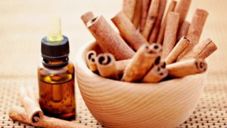一个木碗肉桂棒和一瓶肉桂精油