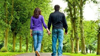 一对夫妇走在公园里,手牵着手