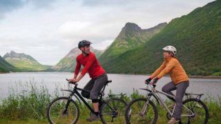 一起骑在路的一对年轻夫妇早晨