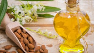 整颗杏仁放在一个乡村调羹里,开花,还有一瓶杏仁精油