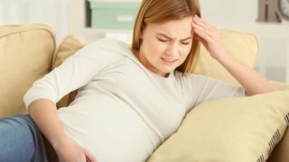 一位孕妇抱着头,脸上带着紧张的表情