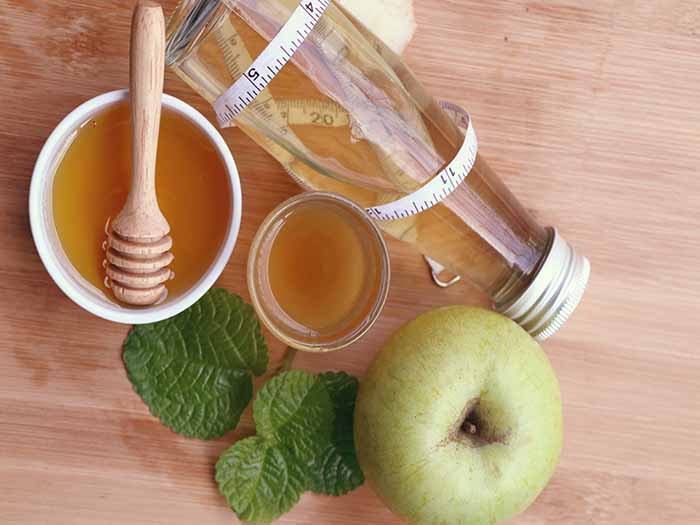苹果醋在玻璃,一个苹果那ACV, and honey on a wooden counter