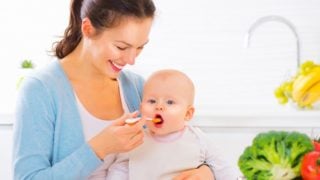 一位快乐的母亲正在给她的婴儿喂食物