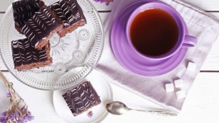 紫色杯子里的香蕉茶,旁边是巧克力布朗尼、香蕉花和方糖