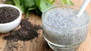 与一碗白色碗的罗勒种子饮料在一张木桌上的干罗勒种子