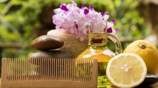 玻璃罐里放着香精油,旁边放着薰衣草花、橘子和一把梳子,放在木桌上。