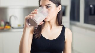 女性在健身房的衣服喝奶昔。