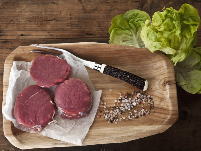 用烤叉将大块的野牛肉放在木托盘上