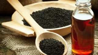 How to Use Black Seed Oil for Weight Loss 木碗和黑茴香籽用勺子在黄麻布一瓶黑孜然油