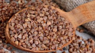 木桌上装满荞麦的木勺的特写镜头