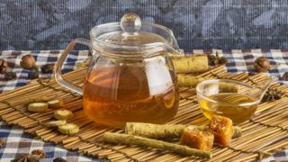 小透明水壶和茶杯,装满了茶和牛蒡根包围