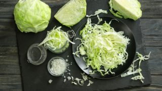 木桌上放着整棵卷心菜和切碎的卷心菜