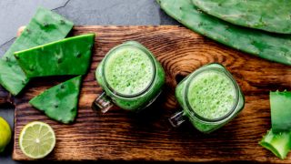 新鲜的仙人掌汁放在木质砧板上,背景是切好的仙人掌片