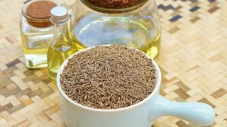 用新鲜的香菜种子香菜油的罐子在一个大的量勺