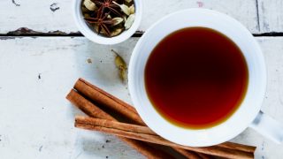 小豆蔻茶,一小碗小豆蔻和茴芹籽,肉桂棒放在白色的木桌上