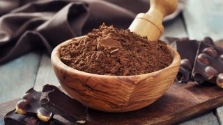 角豆粉放在碗里,木制背景上是巧克力块