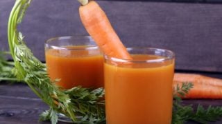 胡萝卜伸出一块黑色的桌子上的两杯胡萝卜汁