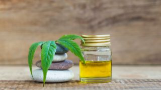 CBD油瓶子旁边光滑的石头和大麻叶