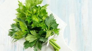 在一个白色切板的整个芹菜在一张蓝色桌上