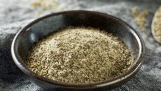 芹菜盐在一个扁平的黑色配料盘中,放在灰色的餐盘上