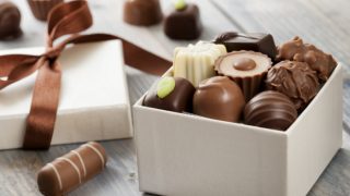 各种巧克力装在一个白色的礼品盒里,上面系着缎带