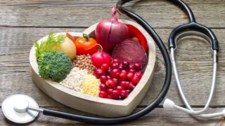 含胆固醇食物(甜菜、豆类、西兰花、番茄、萝卜、甜菜、洋葱等)的心型餐盘,配有听诊器