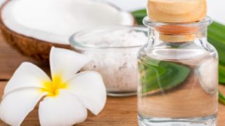一瓶椰子油与椰子奶油小碗里,用白色花朵在木桌上一个椰子减半