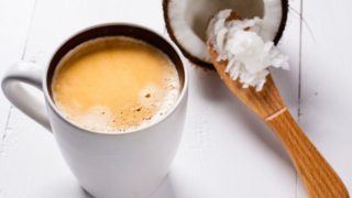 一杯咖啡旁边减半椰子黄油刀铲