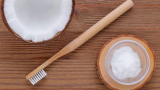 椰子奶油碗和椰子半之间放置在木牙刷的Flatlay视图。