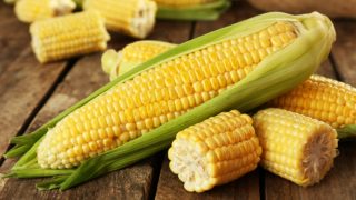 木桌上放着切好的新鲜玉米穗和叶子