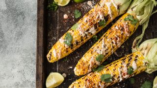 酱,芫荽,石灰,辣椒粉和奶酪烤玉米穗轴的平坦捻图片。