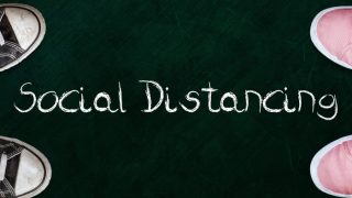 两个人站在黑板上用的字社会距离。