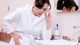 孕妇坐在沙发上抱着她的头,看着强调