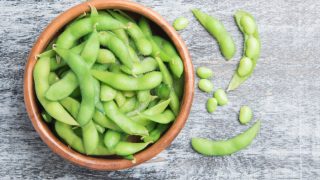 木桌上放着一碗新鲜的毛豆