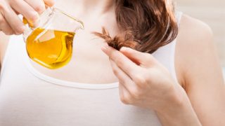 女孩用另一只手拿着一瓶油,用发梢抓着