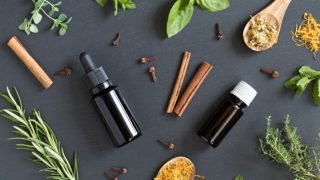 两瓶香精油,旁边是香草、香料和花瓣