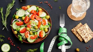 FLATLINE查看沙拉,饼干,在卷尺包裹起来的水和叉的玻璃的,在石板上的背景。