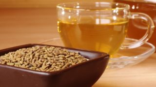 木桌上放着一碗胡芦巴种子和一杯茶