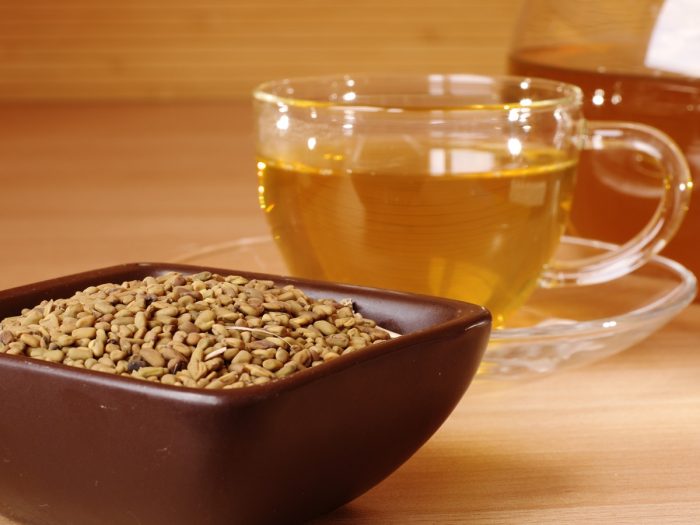 木桌上放着一碗胡芦巴种子和一杯茶