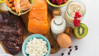 肝脏,鱼,虾,鸡蛋,牛奶,鱼,坚果,奶酪,浆果和燕麦的平面图片。