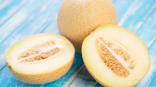 新鲜的整个特写镜头和在一张蓝色木桌上的一半的galia瓜