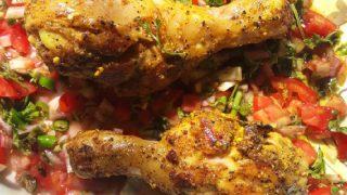 涂有香料的鸡肉,配以番茄洋葱沙拉,并配以柠檬