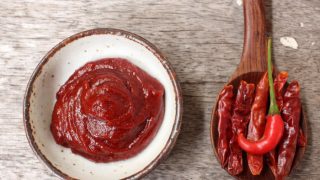 将辣椒酱放在一个白色的小盘子里,旁边放上新鲜的干辣椒