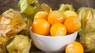 白碗新鲜黄金浆果和浆果在木桌