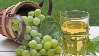 一串葡萄和葡萄汁放在花园的白桌子上