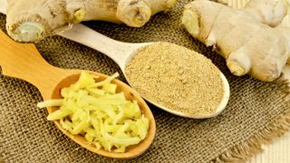 生姜根并排放置含有在粗麻布布磨碎和粉状生姜两匙。