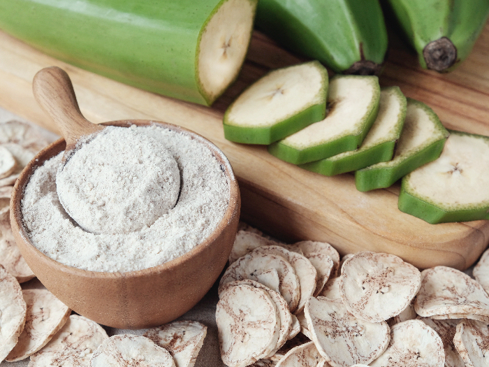 生的绿色香蕉大蕉面粉放在一个碗里,背景是切片大蕉和整大蕉