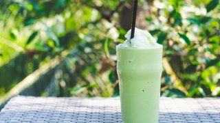 一杯绿茶frappe冰震动与绿色植物背景