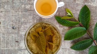 番石榴茶,含有番石榴叶和水的碗,新鲜番石榴叶在木桌上一个杯子