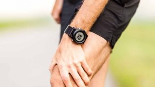 在运行的衣服穿数字手表的男子,手里拿着他的膝盖